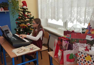 Uczennica siedząca przy keyboardzie i grająca kolędy podczas wigilii klasowej